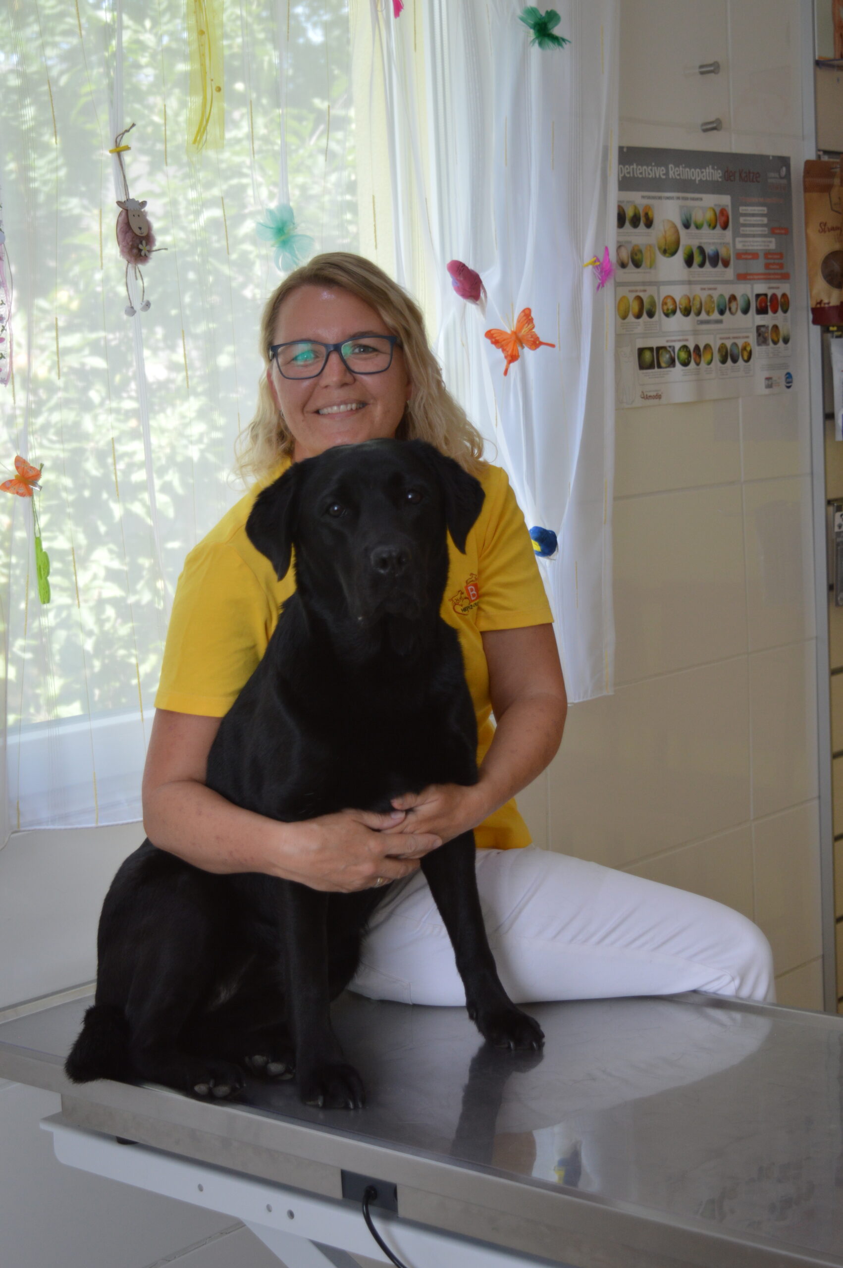 tierarzt-mit-hund.jpg Tierärztin mit einem schwarzen Hund im Behandlungszimmer